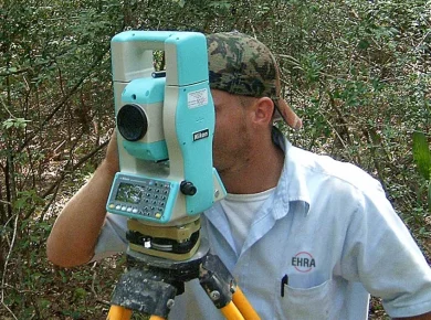 Land surveyor using a theodolite to locate and mark a property line