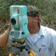 Land surveyor using a theodolite to locate and mark a property line