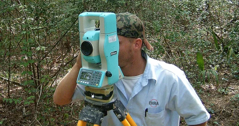 Land surveyor using a theodolite to locate and mark a property line